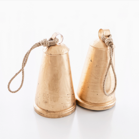 Two brass cowbells with ropes on a white background